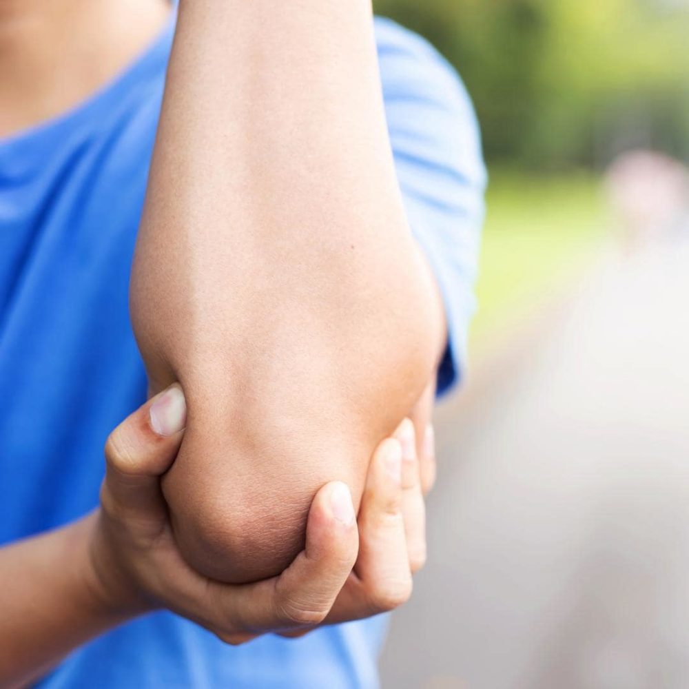 Photo of person holding their elbow, due to tennis elbow.